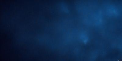 The primary subject of the image is a blue sky with a few clouds. The setting is a dark blue background, which creates a contrasting effect with the clouds. The visual style is a photo, capturing the beauty of the sky and clouds. The colors and mood of the image are predominantly dark and moody, with the blue sky and clouds creating a sense of depth and tranquility.