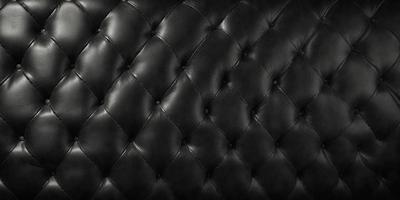 The primary subject of the image is a black leather couch. The setting is a room with a black background, which creates a striking contrast with the couch. The visual style is a close-up of the couch, showcasing its texture and details. The colors and mood of the image are predominantly black, giving it a sleek and modern appearance.