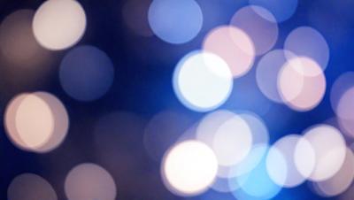 The primary subject of the image is a brightly lit, colorful background featuring a pattern of white lights. The setting appears to be a nighttime cityscape, with the lights creating a vibrant and lively atmosphere. The visual style of the image is a combination of photo and digital art, as it captures the essence of a cityscape at night. The colors and mood of the image are predominantly white and blue, with the white lights creating a sense of energy and excitement.