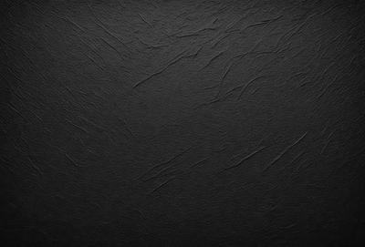 The primary subject of the image is a black background with a pattern of white lines. The setting is a dark room, and the visual style is a close-up of the black background. The colors and mood of the image are predominantly dark and moody, with the white lines adding a touch of contrast.