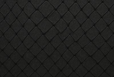 The primary subject of the image is a black and white patterned surface, which appears to be a black leather material. The setting is a close-up of the pattern, showcasing the intricate design. The visual style is a patterned texture, which gives the image a unique and artistic appearance. The colors and mood of the image are predominantly black and white, creating a bold and striking visual effect.