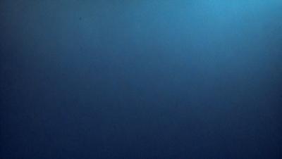 The primary subject of the image is a large, dark blue surface. The setting is a vast, empty space with no visible objects or backdrop. The visual style is a close-up of the blue surface, which gives the impression of a painting or drawing. The colors and mood are predominantly dark and moody, with the blue surface being the main focus of the image.