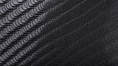 The primary subject of the image is a close-up of a black leather material, possibly a leather jacket or a leather-like fabric. The setting is a black background, which emphasizes the leather material. The visual style is a close-up, focusing on the details of the leather. The colors and mood of the image are predominantly black, giving it a sleek and sophisticated appearance.