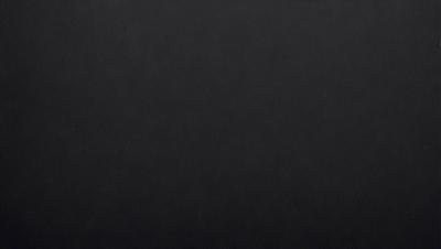 The primary subject of the image is a black background. The setting is a dark room, and the visual style is a black and white photo. The colors and mood of the image are predominantly dark and moody, with a sense of mystery and depth.