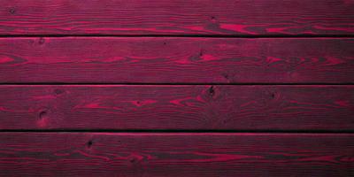 The primary subject of the image is a wooden deck with a red surface. The setting is an outdoor environment, and the visual style appears to be a photo. The dominant colors in the image are red and pink, creating a warm and inviting atmosphere.