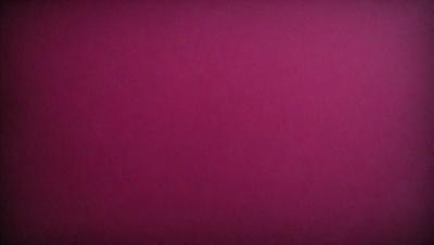 The primary subject of the image is a large, pink wall. The setting is a room with a red background, which creates a bold and striking visual effect. The visual style is a close-up of the wall, emphasizing its color and texture. The dominant colors are red and pink, giving the image a warm and vibrant atmosphere.