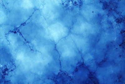 The primary subject of the image is a blue marble wall with a pattern of white and blue swirls. The setting is a room with a blue marble floor. The visual style is a close-up of the marble wall, showcasing the intricate pattern of the swirls. The colors and mood of the image are predominantly blue, creating a serene and calming atmosphere.