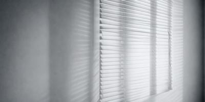 The primary subject of the image is a white shade or blind on a window. The setting is a room with a window, and the visual style is a photo. The colors and mood of the image are predominantly white, giving it a clean and minimalist appearance.