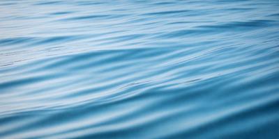 The primary subject of the image is a body of water, which appears to be a large lake. The water is blue and has a few ripples on its surface. The setting is a calm and serene environment, with no visible land or other objects in the background. The visual style of the image is a photo, capturing the natural beauty of the water. The colors and mood of the image are tranquil and soothing, with the blue water and gentle ripples creating a peaceful atmosphere.