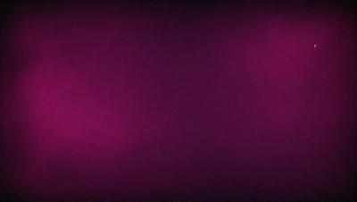The primary subject of the image is a purple background. The setting is a dark, pinkish background that appears to be a wall or a surface. The visual style is a close-up of the purple background, which gives a sense of depth and texture. The colors and mood of the image are predominantly purple, creating a calm and serene atmosphere.