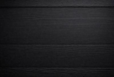 The primary subject of the image is a wooden surface, which appears to be a black wooden wall. The setting is a dark room, and the visual style is a close-up of the wooden surface. The colors and mood of the image are predominantly dark, with the wooden surface being the main focus.