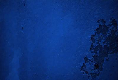 The primary subject of the image is a blue wall with a textured surface. The setting is a room with a blue wall, and the visual style is a photo. The dominant colors are blue and white, creating a calm and serene atmosphere.