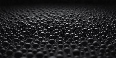 The primary subject of the image is a black and white photo of a large number of small black balls. The setting is a black background, which creates a striking contrast with the balls. The visual style is a close-up of the balls, showcasing their details. The colors and mood of the image are predominantly dark and moody, with the black balls creating a sense of depth and intrigue.