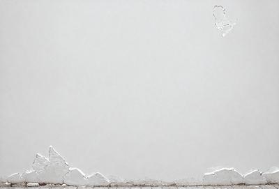 The primary subject of the image is a white wall with a large crack in it. The setting is a room with a white background. The visual style is a photo, and the colors and mood are predominantly white, giving the image a clean and minimalist appearance.