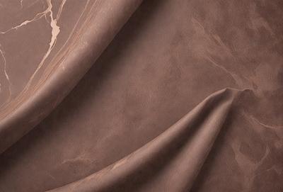 The primary subject of the image is a brown leather material, possibly a piece of fabric or a leather-like surface. The setting is a close-up view of the leather material, showcasing its texture and appearance. The visual style is a detailed, up-close representation of the leather material. The colors and mood of the image are predominantly brown, giving it a warm and natural feel.