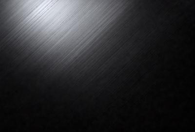 The primary subject of the image is a black background with a silver or grey metal surface. The setting is a dark room, and the visual style is a close-up of the metal surface. The colors and mood of the image are predominantly dark, with the silver or grey metal surface providing a contrasting element.