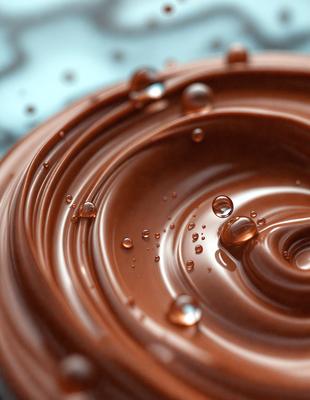 The primary subject of the image is a chocolate sauce, which is the main focus of the scene. The setting is a table, and the visual style is a close-up of the chocolate sauce. The dominant colors are brown and black, giving the image a rich and indulgent atmosphere.