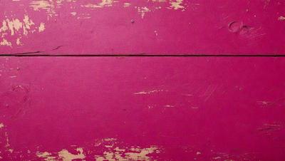 The primary subject of the image is a pink wooden surface. The setting is a room with a pink wall, and the visual style is a close-up of the pink wall. The colors and mood of the image are predominantly pink, creating a warm and inviting atmosphere.