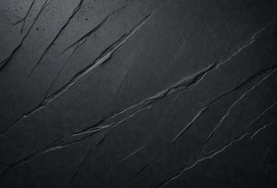 The primary subject of the image is a black surface with a pattern of cracks and crevices. The setting is a dark room, and the visual style appears to be a close-up of the black surface. The colors and mood of the image are predominantly dark and moody, with the black surface creating a dramatic and intense atmosphere.