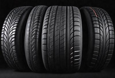 The primary subject of the image is a row of tires. The setting is a black background, and the visual style is a photo. The tires are black and appear to be in good condition. The overall atmosphere is dark and moody, with the tires being the main focus of the image.