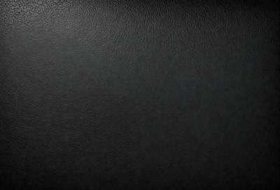 The primary subject of the image is a black leather surface. The setting is a dark room, and the visual style is a close-up of the leather surface. The colors and mood of the image are predominantly dark and moody, with the black leather being the main focus.