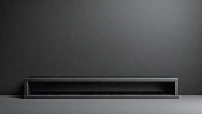 The primary subject of the image is a black laptop computer. The laptop is sitting on a gray surface, which serves as the setting or background. The visual style of the image is a photo, capturing the laptop in its natural environment. The colors and mood of the image are predominantly black and gray, giving it a sleek and modern appearance.