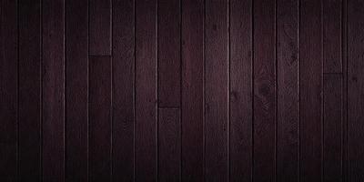 The primary subject of the image is a wooden floor. The setting is a dark room with a wooden floor, which is the main object of the image. The visual style is a photo, and the colors and mood are dark and moody.