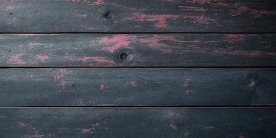 The primary subject of the image is a wooden surface with a pinkish hue. The setting is a wooden wall, and the visual style appears to be a photo. The dominant colors are pink and black, creating a mood of warmth and contrast.