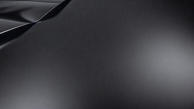 The primary subject of the image is a black surface, which appears to be a piece of cloth or a piece of paper. The setting is a dark room, and the visual style is a close-up of the black surface. The colors and mood of the image are predominantly dark and moody, with the black surface being the main focus of the image.