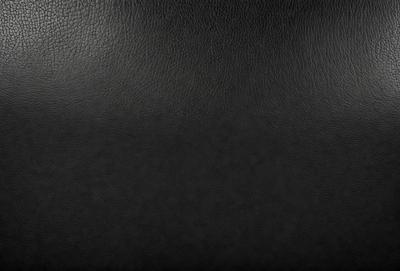 The primary subject of the image is a black leather seat. The setting is a black background, which creates a contrast with the leather seat. The visual style is a close-up of the leather seat, showcasing its texture and details. The colors and mood of the image are predominantly dark, with the black leather seat being the main focal point.