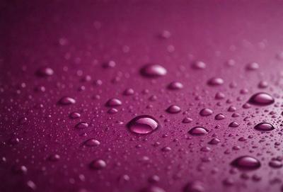 The primary subject of the image is a purple surface with water droplets on it. The setting is a purple background, and the visual style is a close-up of the purple surface with water droplets. The colors and mood of the image are predominantly purple, creating a calm and serene atmosphere.