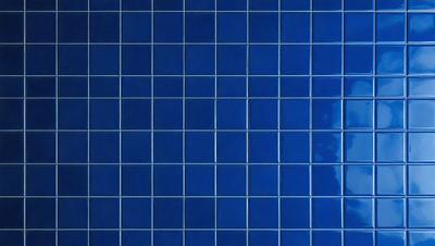 The primary subject of the image is a blue tile wall. The setting is a room with a blue tile wall, and the visual style is a photo. The dominant colors are blue and white, creating a calm and soothing atmosphere.