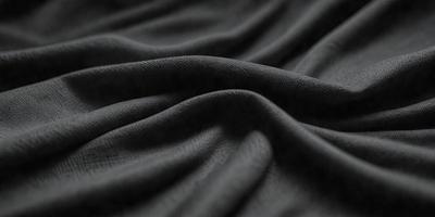 The primary subject of the image is a black fabric, which is the main object, scene, or focus of the image. The setting or background is a dark room, and the visual style is a photo. The colors and mood of the image are predominantly dark and moody, with the black fabric being the dominant color.