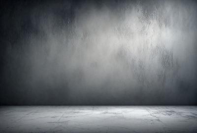The primary subject of the image is a large, empty room with a white wall. The setting is a plain, white room with a concrete floor. The visual style is a photo, and the colors and mood are predominantly white, giving the room a clean and minimalist appearance.