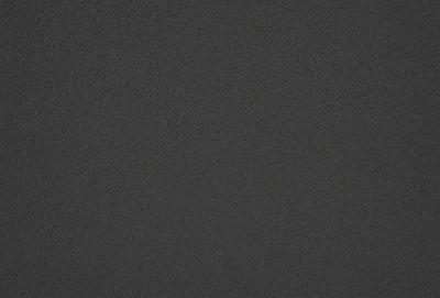 The primary subject of the image is a dark grey surface, which appears to be a textured wall or a dark grey carpet. The setting is indoors, with the surface being the main focus of the image. The visual style is a close-up of the surface, showcasing its texture and color. The colors and mood of the image are dark and moody, with the grey surface being the dominant color.