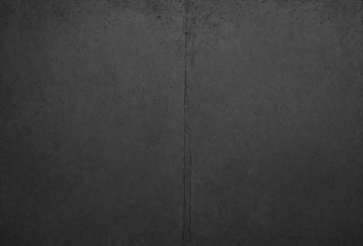 The primary subject of the image is a wall with a gray surface. The setting is a room with a concrete wall, and the visual style is a photo. The dominant colors are gray and black, creating a moody atmosphere.