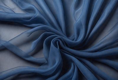 The primary subject of the image is a blue fabric, possibly a piece of cloth or a curtain, with a swirling pattern. The setting is a white background, which provides a clean and uncluttered look. The visual style is a close-up of the blue fabric, showcasing its texture and pattern. The colors and mood of the image are predominantly blue, creating a calm and serene atmosphere.
