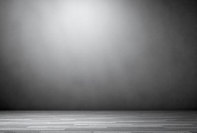 The primary subject of the image is a large, empty room with a black background. The setting is a dark, foggy environment, creating a mysterious and moody atmosphere. The visual style is a black and white photo, which adds to the dramatic and artistic nature of the scene. The colors and mood are predominantly dark and somber, with the fog and darkness enhancing the overall mood of the image.