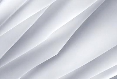 The primary subject of the image is a white wall with a pattern of folded paper. The setting is a room with a white background, and the visual style is a close-up of the paper pattern. The colors and mood of the image are predominantly white, giving it a clean and minimalist appearance.