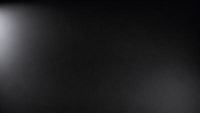The primary subject of the image is a black background. The setting is a dark room, and the visual style is a black and white photo. The colors and mood of the image are predominantly dark and moody, with a sense of mystery and depth.