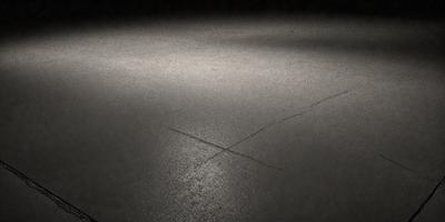The primary subject of the image is a large X drawn on a dark surface, possibly a black floor or a black background. The setting appears to be a dark room or a dark surface, which contrasts with the bright X. The visual style of the image is a simple, bold line drawing, with no additional elements or colors. The colors and mood of the image are predominantly dark, with the X being the only bright element in the scene.