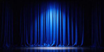 The primary subject of the image is a blue curtain, which is the main object, scene, or focus of the image. The setting is a stage, with the curtains serving as the backdrop. The visual style is a photo, capturing the curtains in their natural environment. The colors and mood of the image are predominantly blue, creating a calm and serene atmosphere.