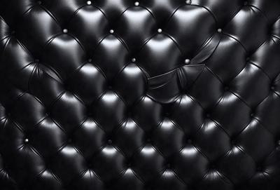 The primary subject of the image is a black leather couch. The setting is a room with a black leather couch as the main object. The visual style is a close-up of the couch, showcasing its texture and design. The colors and mood of the image are predominantly black, giving it a sleek and modern appearance.