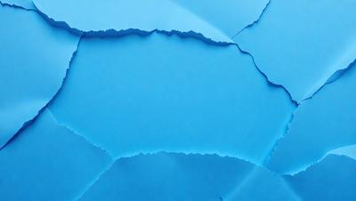 The primary subject of the image is a blue piece of paper with a cutout of a blue sky. The paper appears to be a piece of art or a decoration. The setting is indoors, with the paper placed on a table. The visual style is a combination of a photo and a cutout, creating a unique and artistic appearance. The colors and mood of the image are predominantly blue, giving it a calm and serene atmosphere.