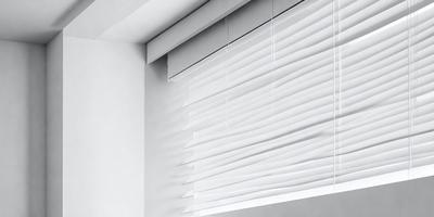 The primary subject of the image is a white shade, which is a window covering. The setting is a room with a white wall, and the visual style is a photo. The colors and mood of the image are predominantly white, giving it a clean and minimalist appearance.