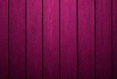 The primary subject of the image is a wooden wall with a purple color. The setting is a room with a wooden surface, and the visual style is a close-up of the wooden wall. The dominant colors are purple and brown, creating a warm and cozy atmosphere.