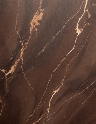 The image features a brown marble wall with a unique pattern of yellow streaks. The wall appears to be made of stone, and the yellow streaks add a distinctive touch to the overall appearance. The setting is a room with a brown color scheme, which complements the marble wall. The visual style of the image is a close-up of the marble wall, showcasing its intricate pattern and texture. The colors and mood of the image are warm and earthy, with the yellow streaks adding a touch of