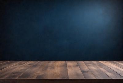 The primary subject of the image is a wooden table with a blue wall in the background. The table appears to be empty, with no objects or items on it. The setting is a simple, clean environment, and the visual style is a realistic representation of the table and wall. The colors and mood of the image are predominantly blue, creating a calm and serene atmosphere.