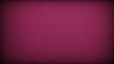 The primary subject of the image is a large, pink surface. The setting is a dark room, and the visual style appears to be a photo. The dominant colors are pink and purple, creating a warm and inviting atmosphere.
