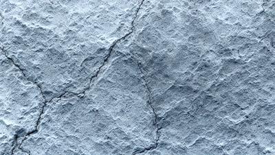 The primary subject of the image is a cracked, textured surface, possibly a stone wall or a concrete wall. The setting is an outdoor environment, with the cracked surface as the main object. The visual style is a close-up of the cracked surface, which gives a sense of depth and texture. The colors and mood of the image are predominantly gray and blue, with the cracked surface adding a sense of age and wear.